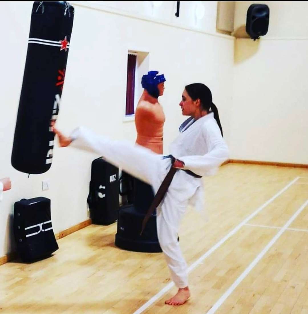 Resolving pain manage neurodiversity Blackbelt woman kicking training bag